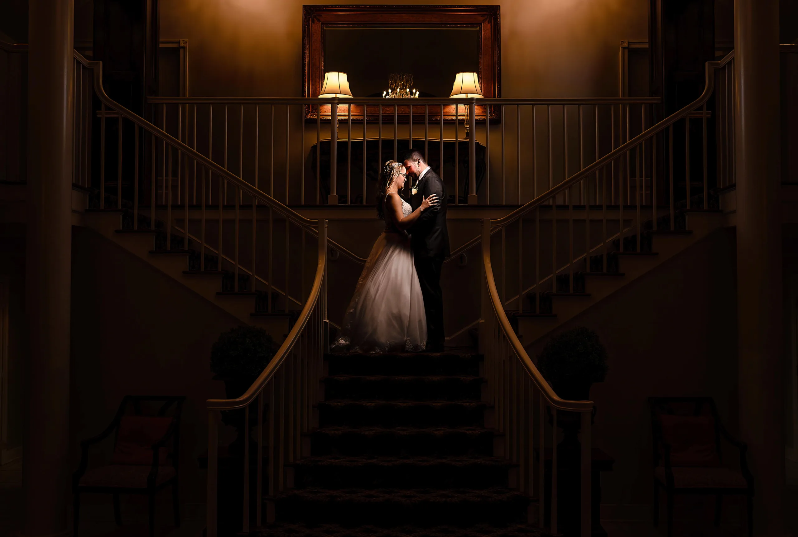 Bride and groom sharing an intimate moment on the grand staircase of the Connecticut wedding venue The Woodwinds