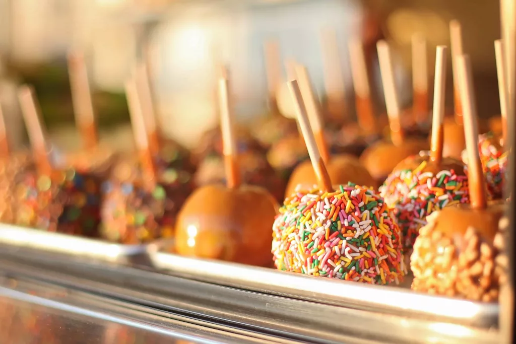 A close-up photo of caramel apples on sticks, with the caramel coating smoothly covering the apples.