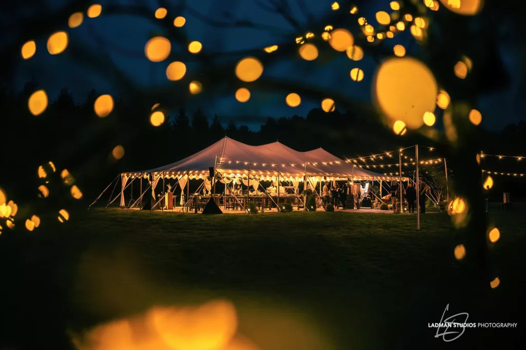 venue tent at barn and farm venue glowing at night surrounded by lights