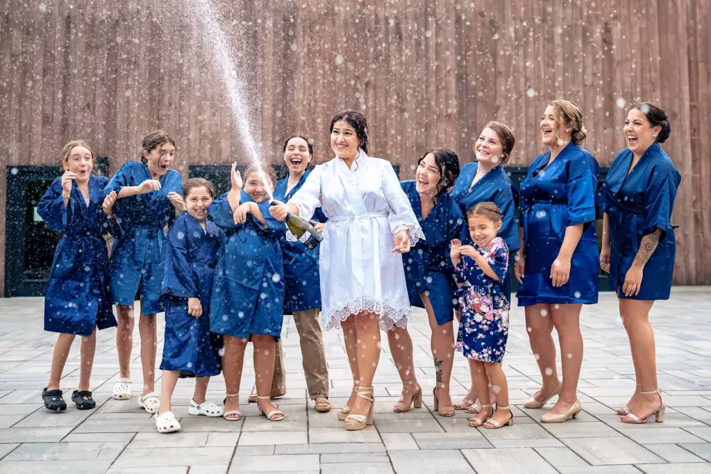 Bride and bridal party spraying champagne at a barn and farm wedding venue