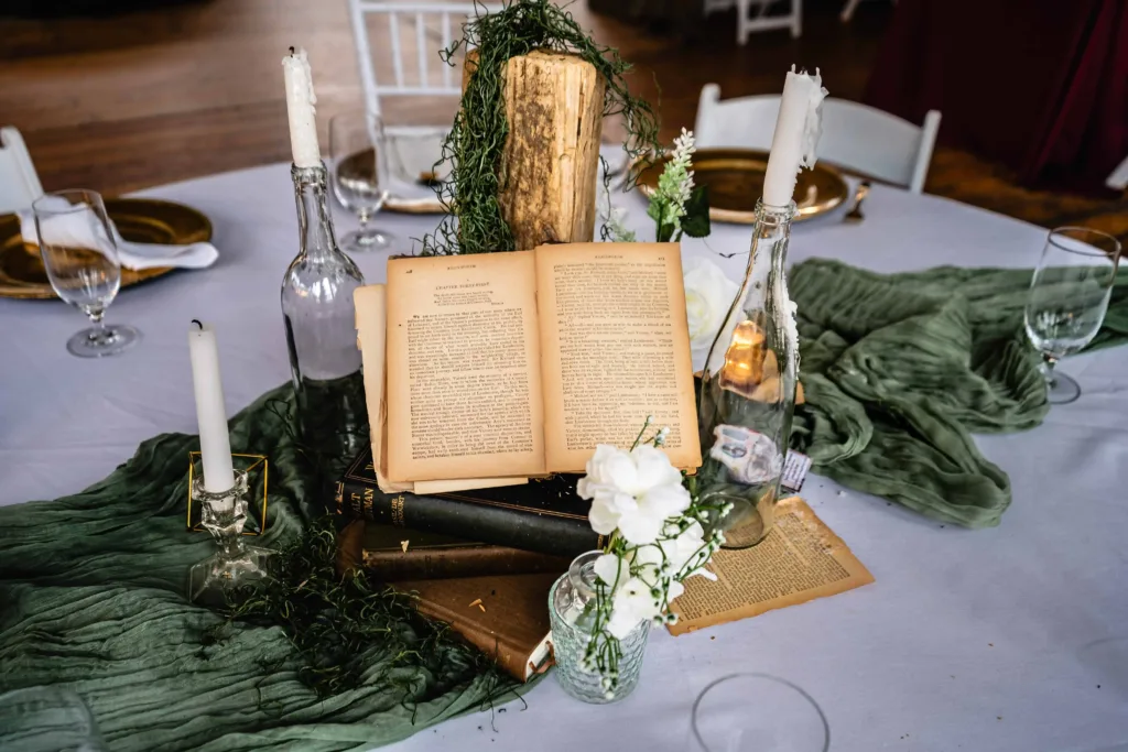 Charming vintage book centerpiece with rustic candles and fresh florals set for a wedding reception at The Lace Factory, showcasing unique table decor in Deep River, Connecticut.