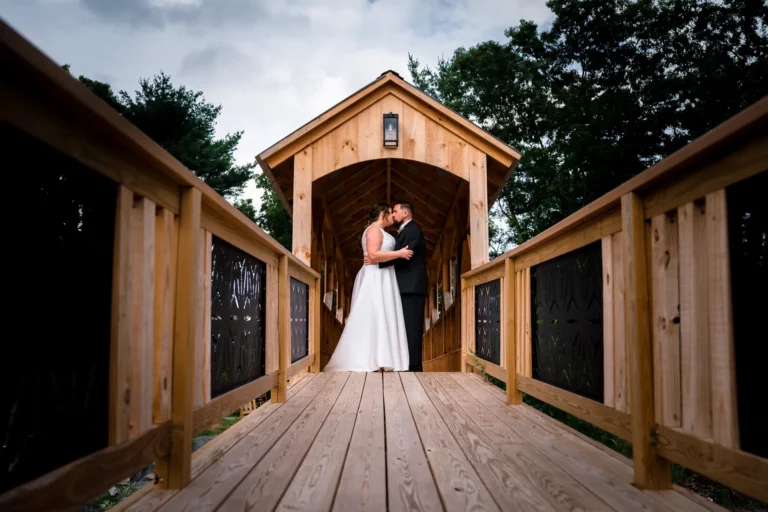 A bride and groom share an intimate moment on a wooden covered bridge surrounded by nature, taken by a Connecticut wedding photographe