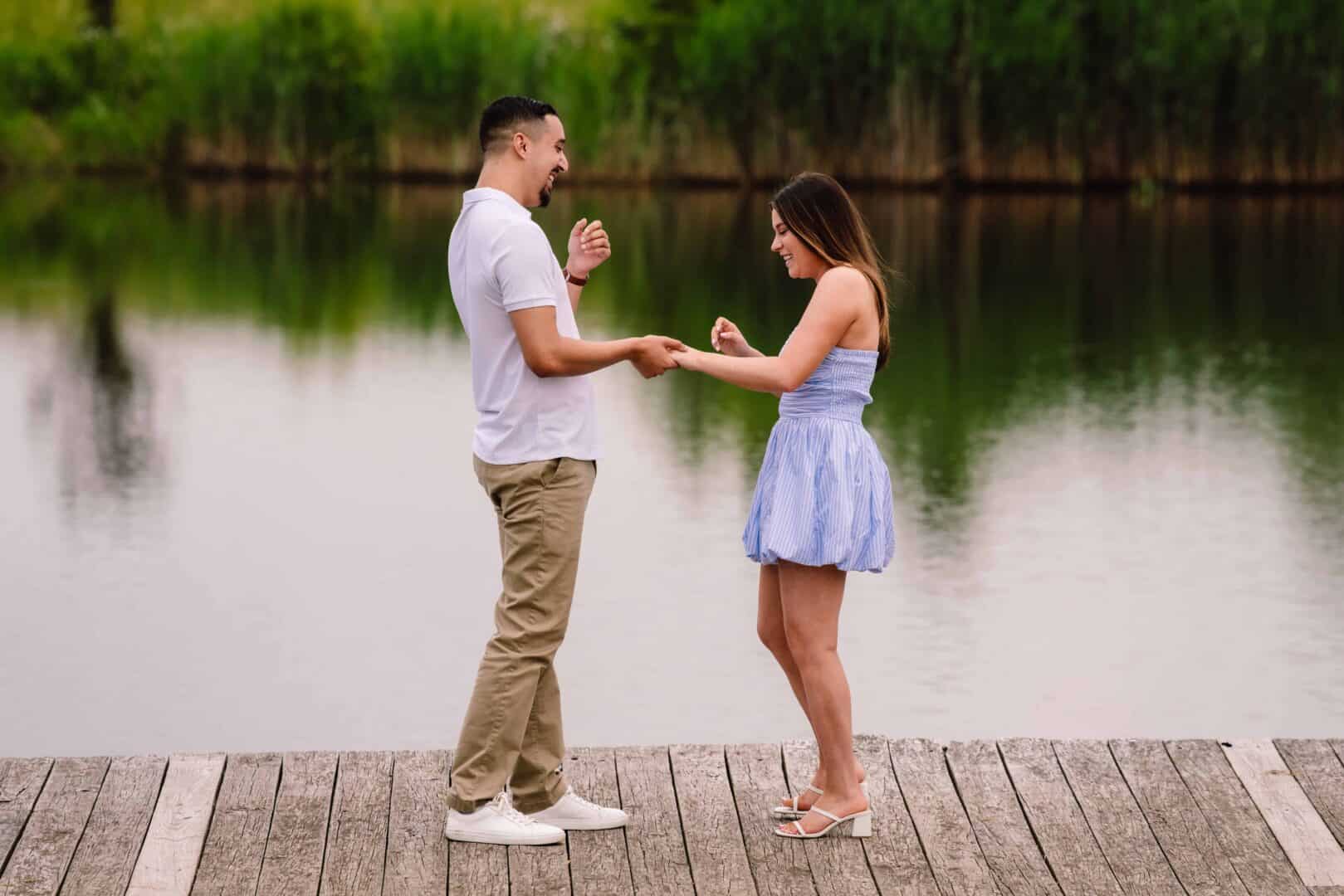 A man and woman are standing on a dock by a lake