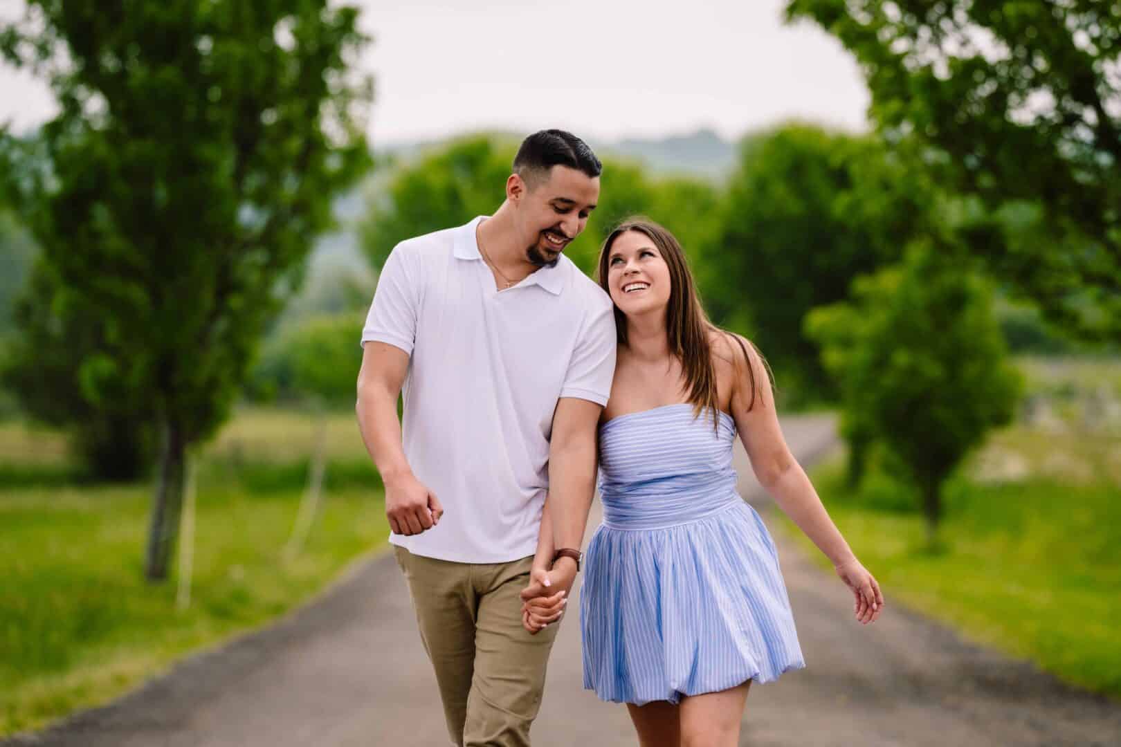 a man and woman holding hands and walking on a road